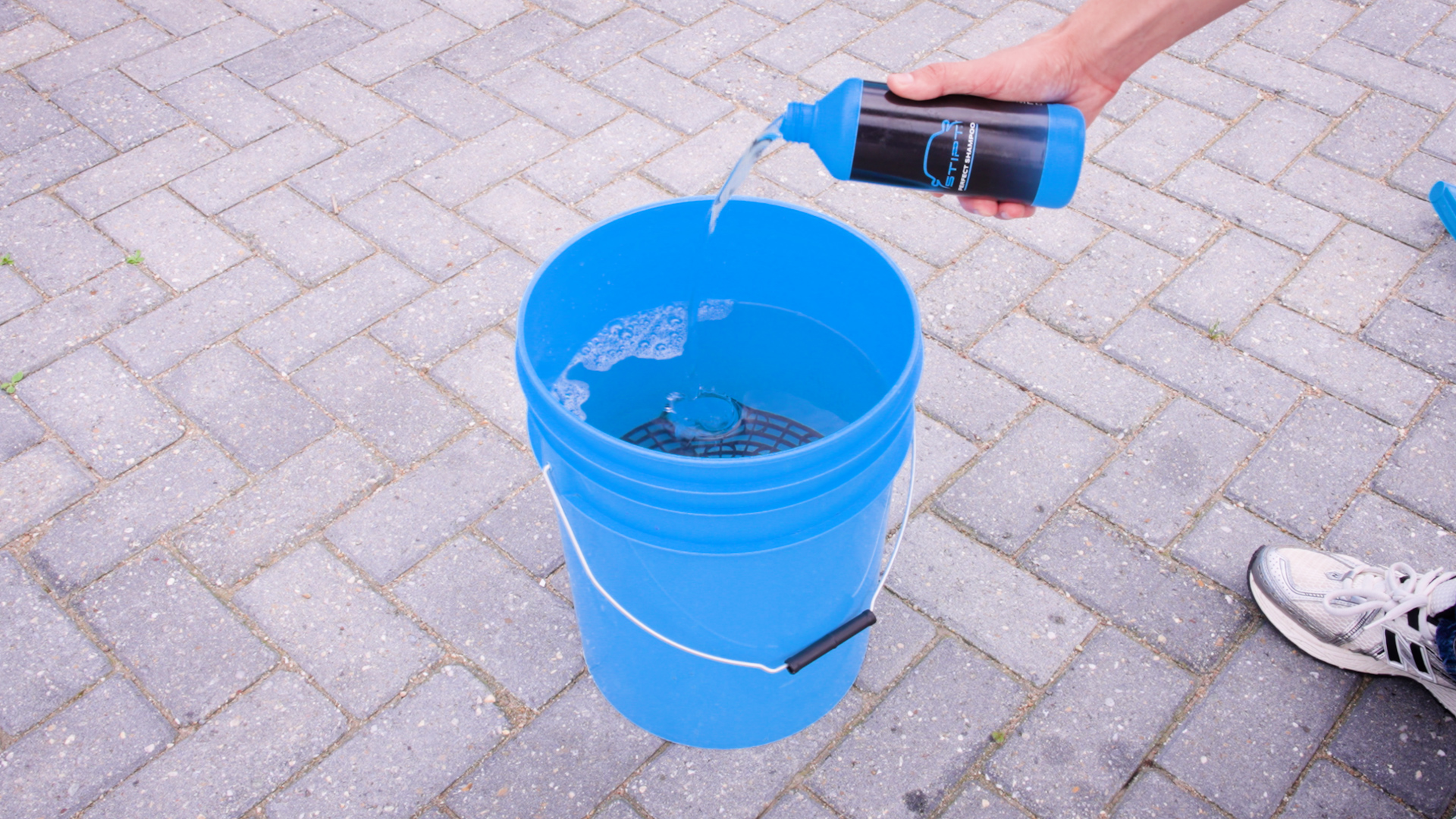 Stipt Perfect Shampoo wordt in een blauwe wasemmer gegoten voor het voorbereiden van een veilige was
